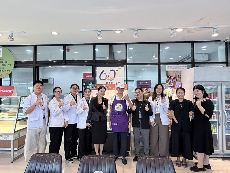 Group photo of students, professor, and APCD staff with a person with visual impairment (total blindness), working at the APCD 60+ Bakery & Chocolate Café project.