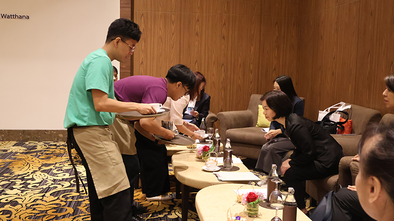 ภาพที่ 3: ผู้เข้าอบรมใส่เสื้อสีม่วง และ ผู้เข้าอบรมใส่เสื้อสีม่วง (ซ้าย) กำลังนำของว่างและเครื่องดื่มให้ คุณ Komahashi Rie - Senior Representative (ขวา)