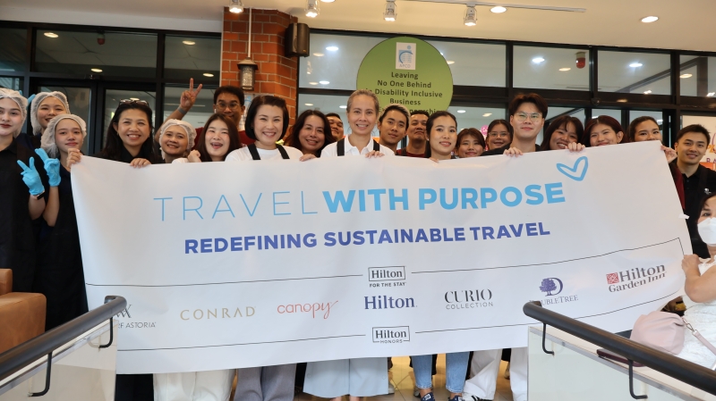 Representatives from three hotels hold a 'Travel with Purpose' sign while posing for a photo after a bakery workshop session.