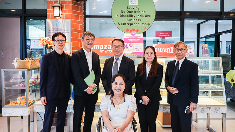 Picture 11: From left to right, Mr. SAKUDO Shunsuke, Mr. KOBAYASHI Hiroyuki, Mr. Piroon Laismit, Ms. Nuntaporn Sittidetboripat, Mr. Somchai Rungsilp, and Ms. Nongnuch Maytarjittipun (seated in a wheelchair in front of Mr. Piroon Laismit) pose for a group photo