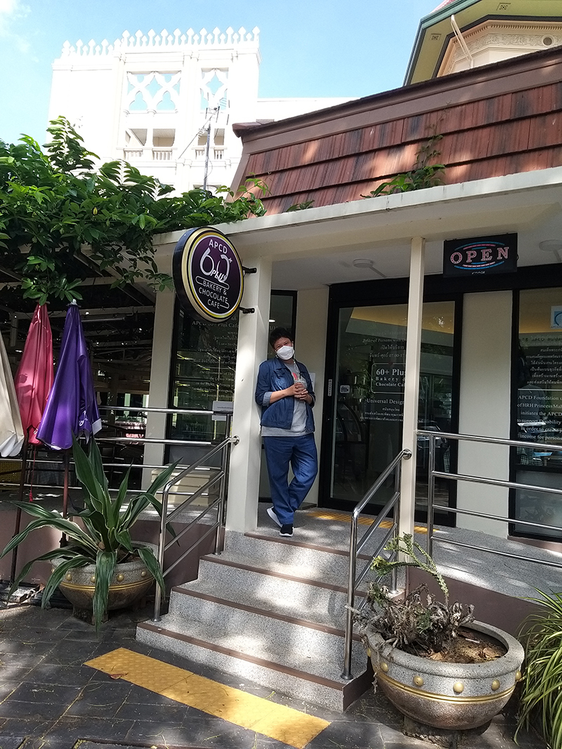 A self-advocate with intellectual disability from Chiang Mai, posed in front of the APCD 60+plus bakery and café shop at the Government House. 