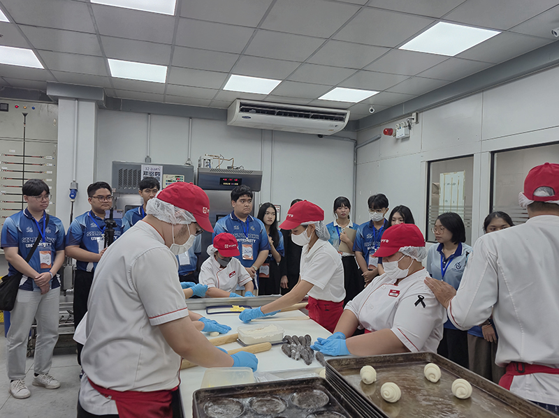 คณะนักศึกษาสังเกตุการณ์โครงการ DIB ที่พนักงานพิการกำลังทำขนมปังในร้าน APCD 60+ Plus Bakery & Café