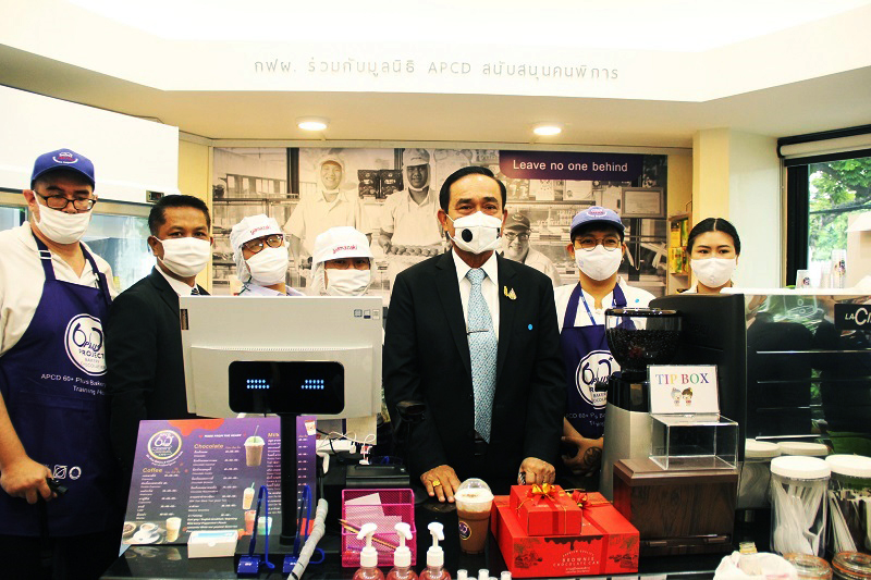 Group photo of the Prime Minister with café staff with disabilities inside the café. 